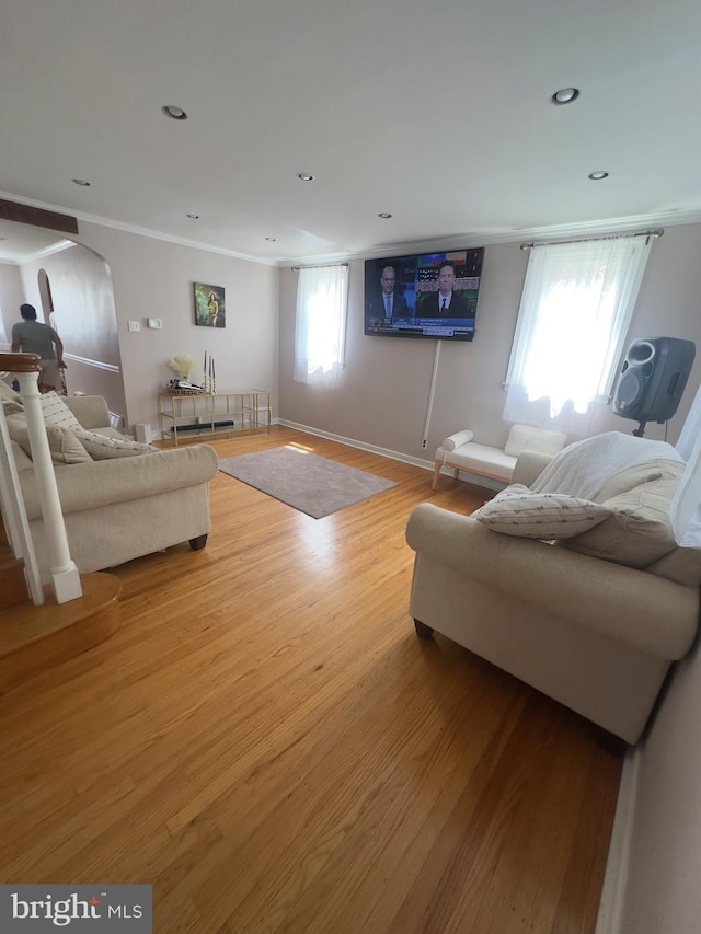 living area featuring recessed lighting, crown molding, baseboards, arched walkways, and wood finished floors