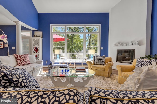 living area with ornate columns, baseboards, and wood finished floors