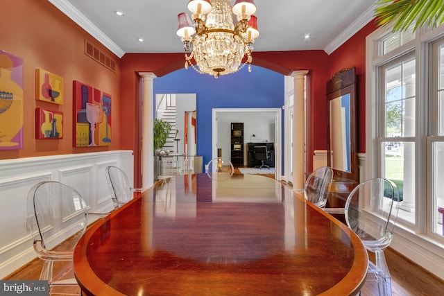 dining room with crown molding, a notable chandelier, wood finished floors, ornate columns, and visible vents