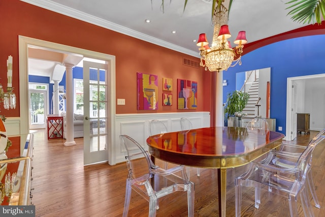 dining room featuring decorative columns, visible vents, wood finished floors, a wainscoted wall, and a chandelier
