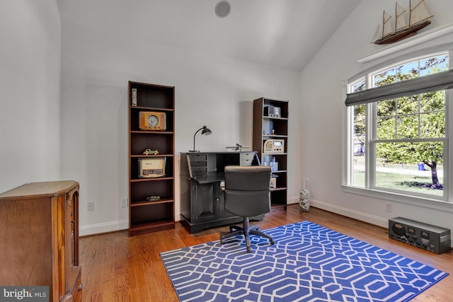 home office with baseboards, wood finished floors, and high vaulted ceiling