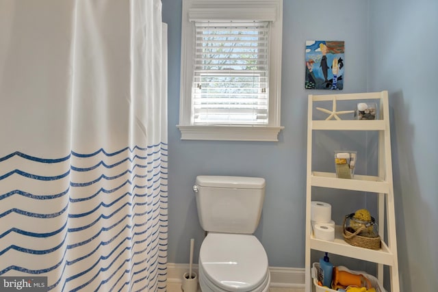 bathroom featuring a shower with curtain, baseboards, and toilet