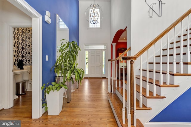 foyer featuring stairs, an inviting chandelier, wood finished floors, and a towering ceiling