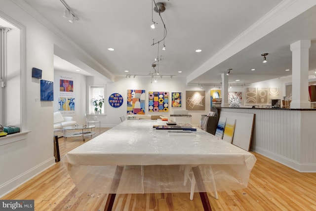 dining room with ornate columns, rail lighting, light wood finished floors, and baseboards