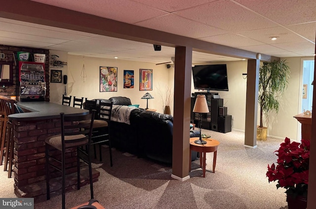 interior space featuring baseboards, carpet, a drop ceiling, and a dry bar