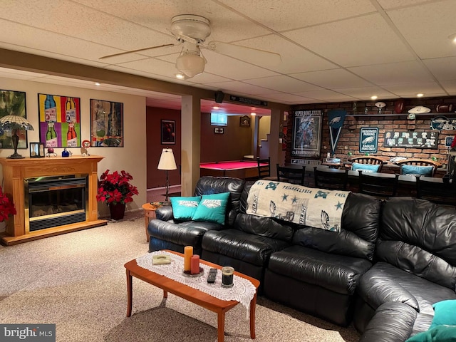 living area featuring baseboards, carpet, a glass covered fireplace, and a drop ceiling