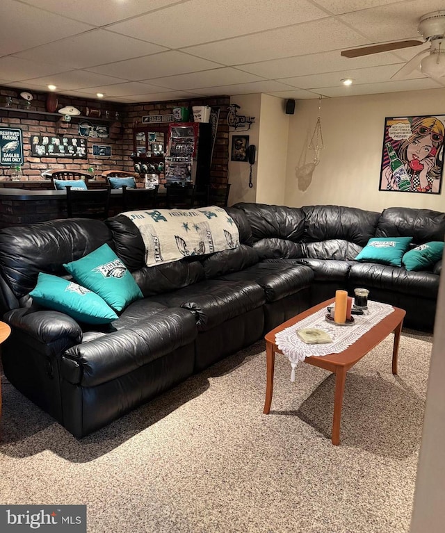 carpeted living area with a ceiling fan and a paneled ceiling