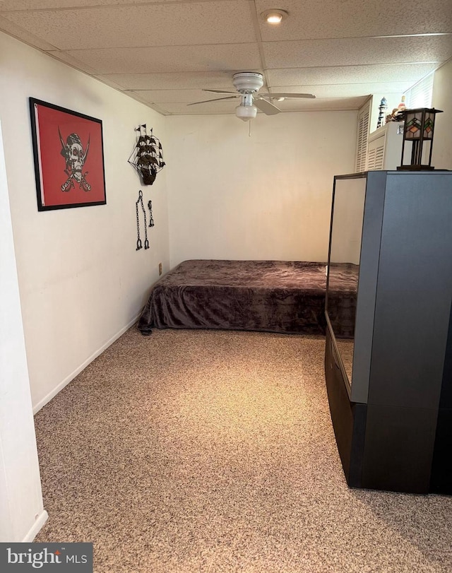 carpeted bedroom featuring baseboards, a drop ceiling, and ceiling fan