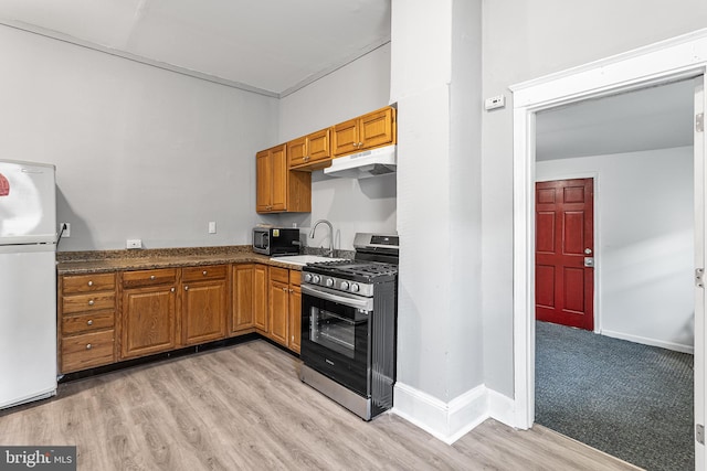 840 Cumberland St, Gloucester City, NJ 08030 - kitchen with stainless steel appliances, under cabinet range hood, a sink, brown cabinetry, and light wood-style floors