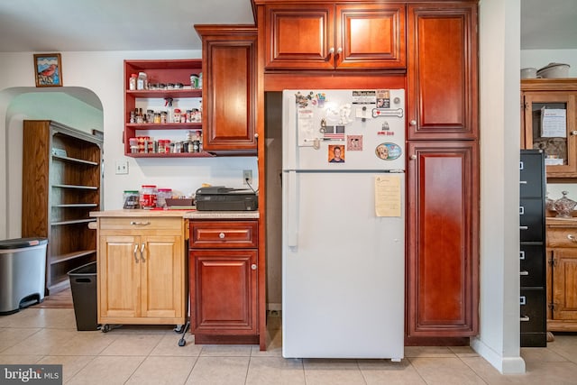 kitchen featuring freestanding refrigerator, light countertops, light tile patterned floors, and open shelves