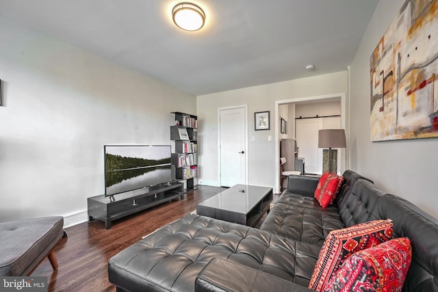 living area featuring a barn door, baseboards, and wood finished floors