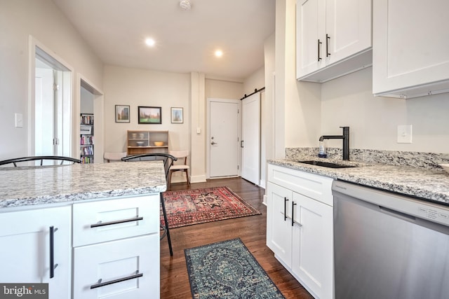 kitchen featuring stainless steel dishwasher, light stone countertops, dark wood-style floors, white cabinetry, and a sink