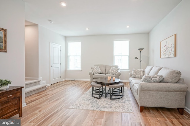 living area with stairs, baseboards, a wealth of natural light, and light wood-style flooring