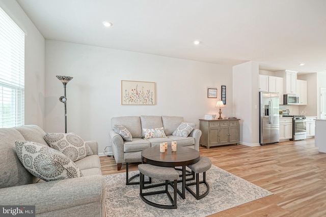 living room with baseboards, recessed lighting, and light wood-style flooring