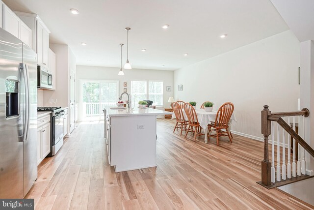 kitchen with a sink, appliances with stainless steel finishes, white cabinets, and light wood-style floors