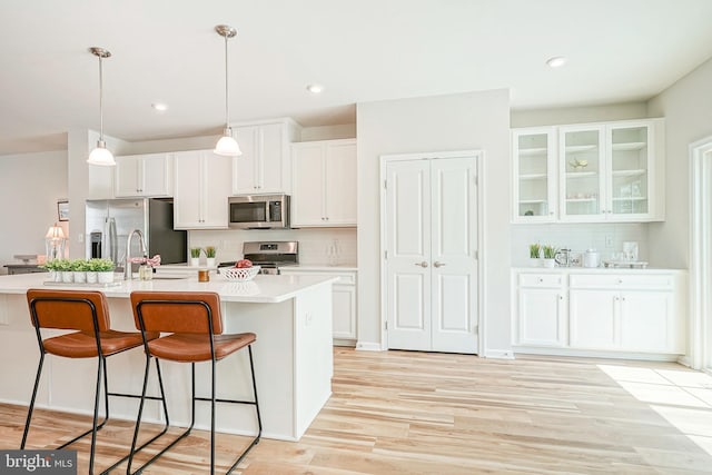 kitchen featuring white cabinets, stainless steel appliances, decorative backsplash, and a kitchen breakfast bar