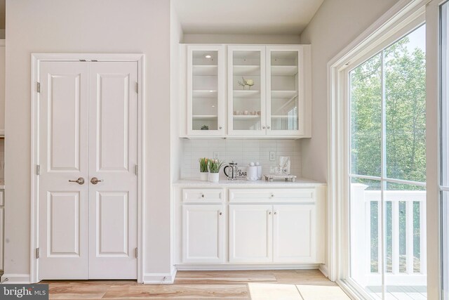 bar featuring light wood-style floors and backsplash