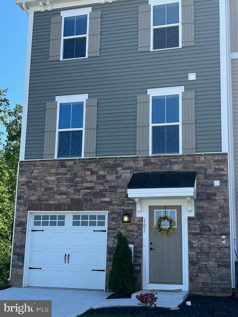 view of front of home featuring an attached garage and stone siding