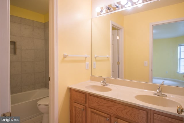 bathroom featuring toilet, double vanity, a sink, and tile patterned floors