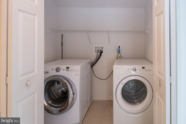 laundry room with light tile patterned floors, washing machine and clothes dryer, and laundry area