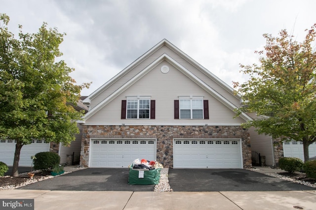 traditional home featuring driveway and stone siding