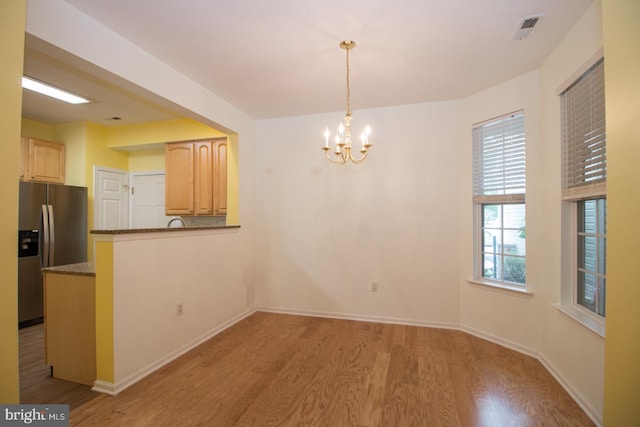 unfurnished dining area featuring visible vents, baseboards, a chandelier, and light wood-style floors