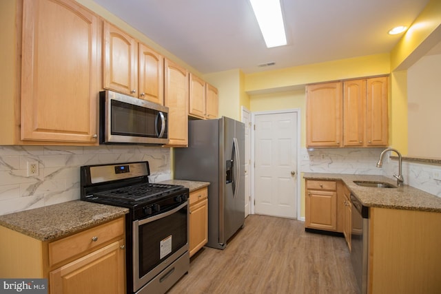 kitchen with light stone countertops, light brown cabinets, appliances with stainless steel finishes, and a sink