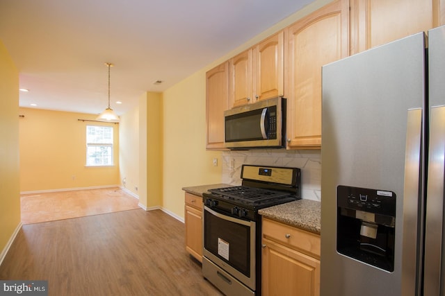 kitchen featuring light wood-style floors, tasteful backsplash, light brown cabinetry, baseboards, and appliances with stainless steel finishes