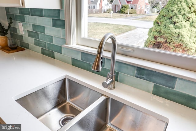 interior details with a sink, decorative backsplash, and light countertops
