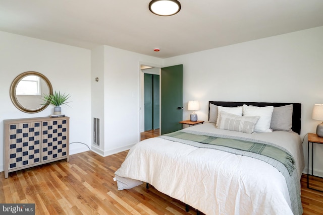 bedroom featuring wood finished floors, visible vents, and baseboards