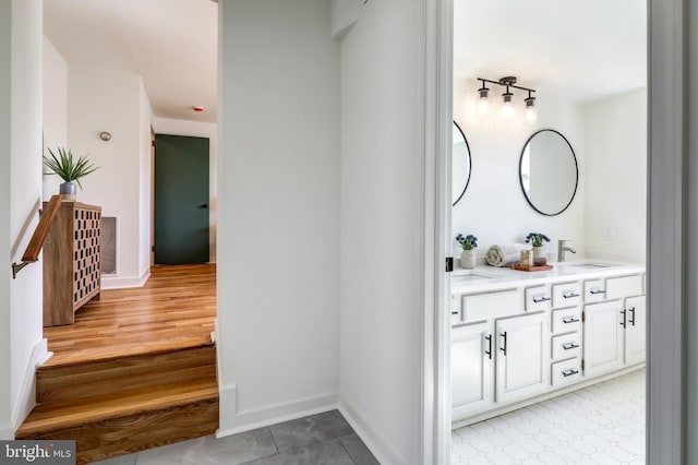 bathroom featuring double vanity, baseboards, and a sink