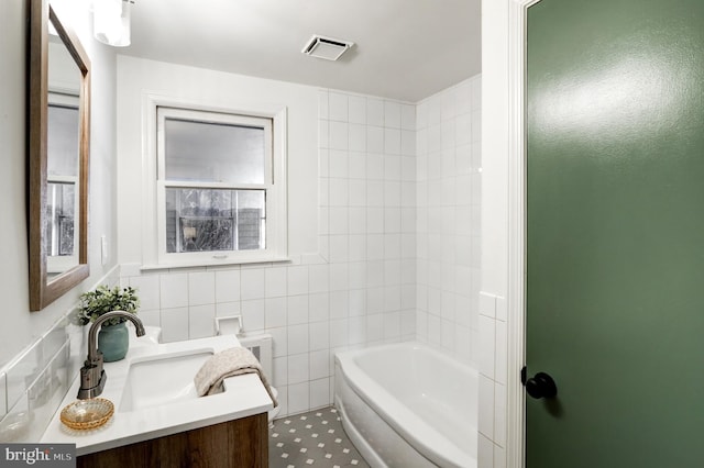 full bath with visible vents, vanity, and tile walls