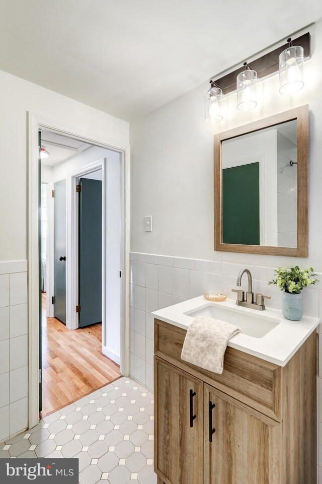 bathroom with tile walls, tile patterned floors, a wainscoted wall, and vanity