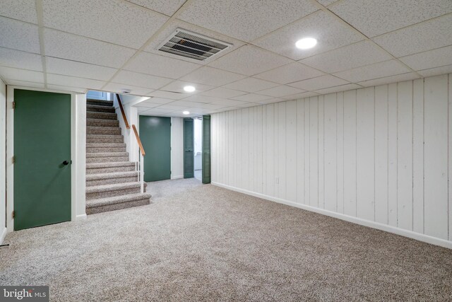 finished below grade area featuring visible vents, a paneled ceiling, stairs, and carpet floors