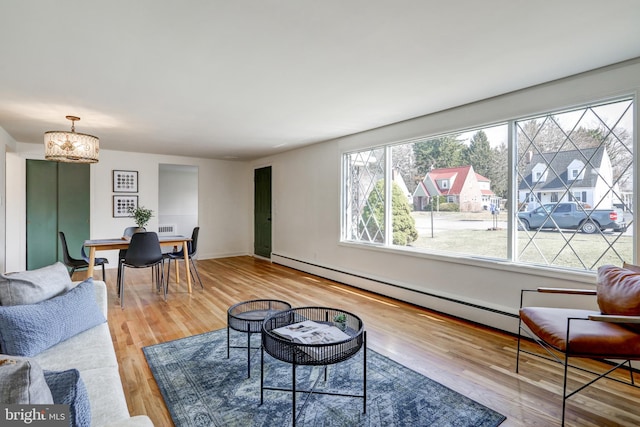 living area featuring visible vents, baseboard heating, baseboards, wood finished floors, and a notable chandelier
