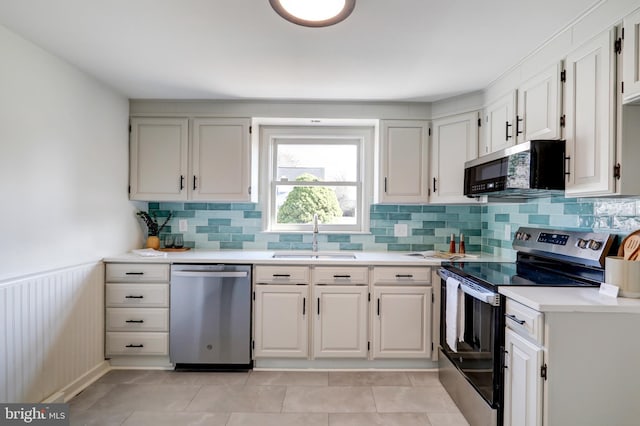 kitchen with tasteful backsplash, a sink, appliances with stainless steel finishes, and light countertops