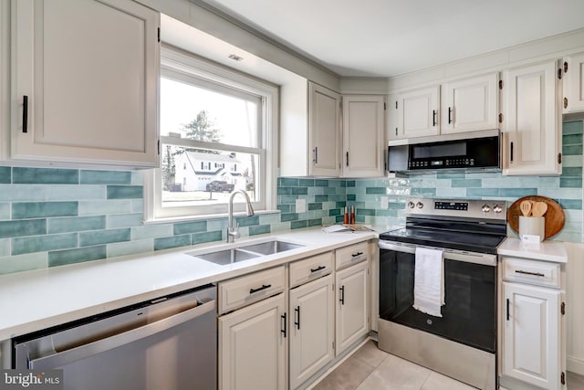 kitchen with a sink, backsplash, light countertops, white cabinets, and appliances with stainless steel finishes