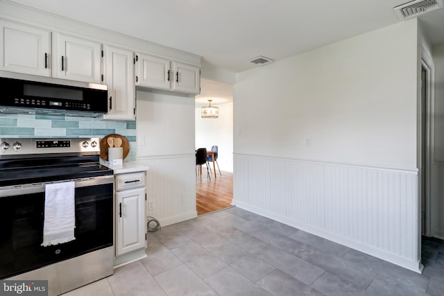 kitchen with visible vents, stainless steel appliances, a wainscoted wall, and white cabinets
