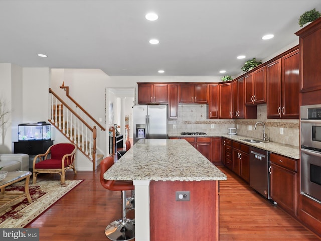 43260 Mitcham Sq, Ashburn, VA 20148 - kitchen featuring light wood-style floors, appliances with stainless steel finishes, dark brown cabinets, a sink, and a kitchen breakfast bar