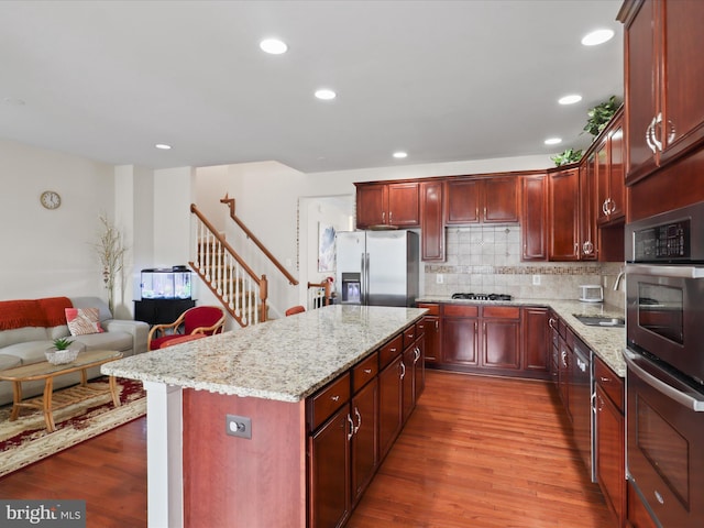 43260 Mitcham Sq, Ashburn, VA 20148 - kitchen featuring stainless steel appliances, dark brown cabinets, a kitchen island, light stone countertops, and dark wood-type flooring