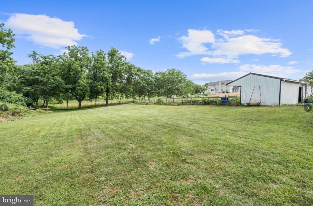 view of yard featuring fence, a pole building, and an outbuilding