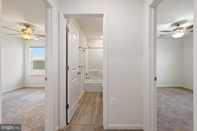 hall with baseboards and light colored carpet