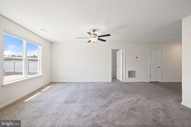 empty room featuring carpet floors, ceiling fan, visible vents, and baseboards
