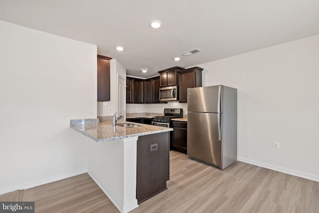 kitchen with dark brown cabinetry, light wood-style flooring, stainless steel appliances, a peninsula, and visible vents