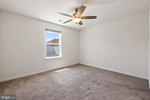 spare room with carpet floors, ceiling fan, visible vents, and baseboards
