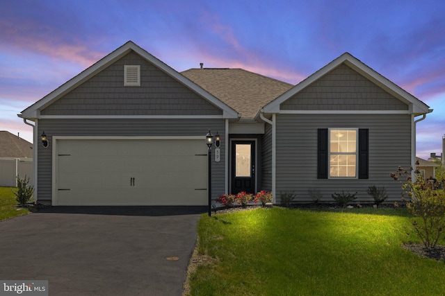ranch-style house with a garage, a lawn, and aphalt driveway