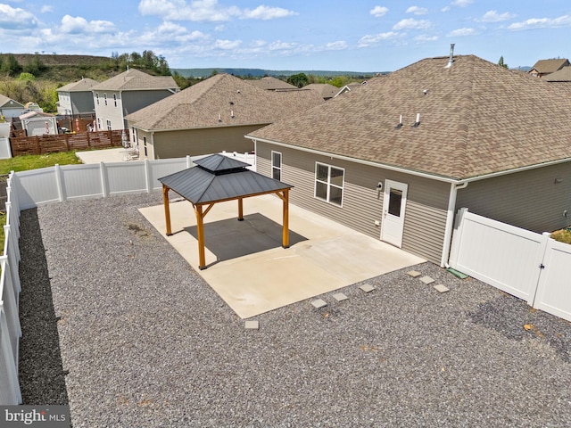 rear view of house featuring roof with shingles, a residential view, a patio area, a gazebo, and a fenced backyard