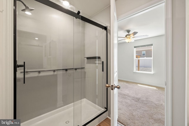 bathroom featuring baseboards, ceiling fan, and a shower stall