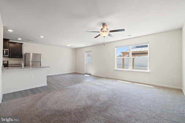 unfurnished living room with light colored carpet, baseboards, ceiling fan, and visible vents