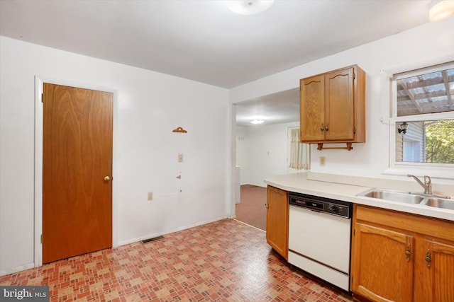kitchen featuring visible vents, dishwasher, a sink, light countertops, and baseboards